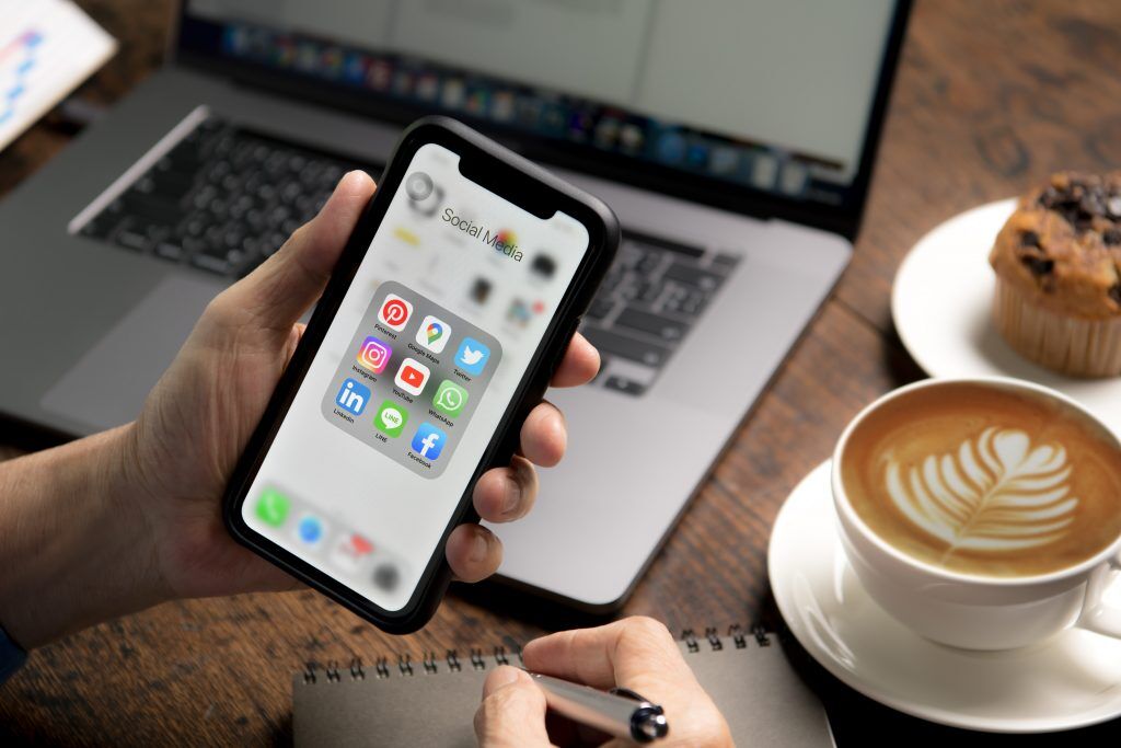 Where Can I Find Reputable Aircon Company In Singapore? 9 person holding smartphone with icons social media screen coffee shop