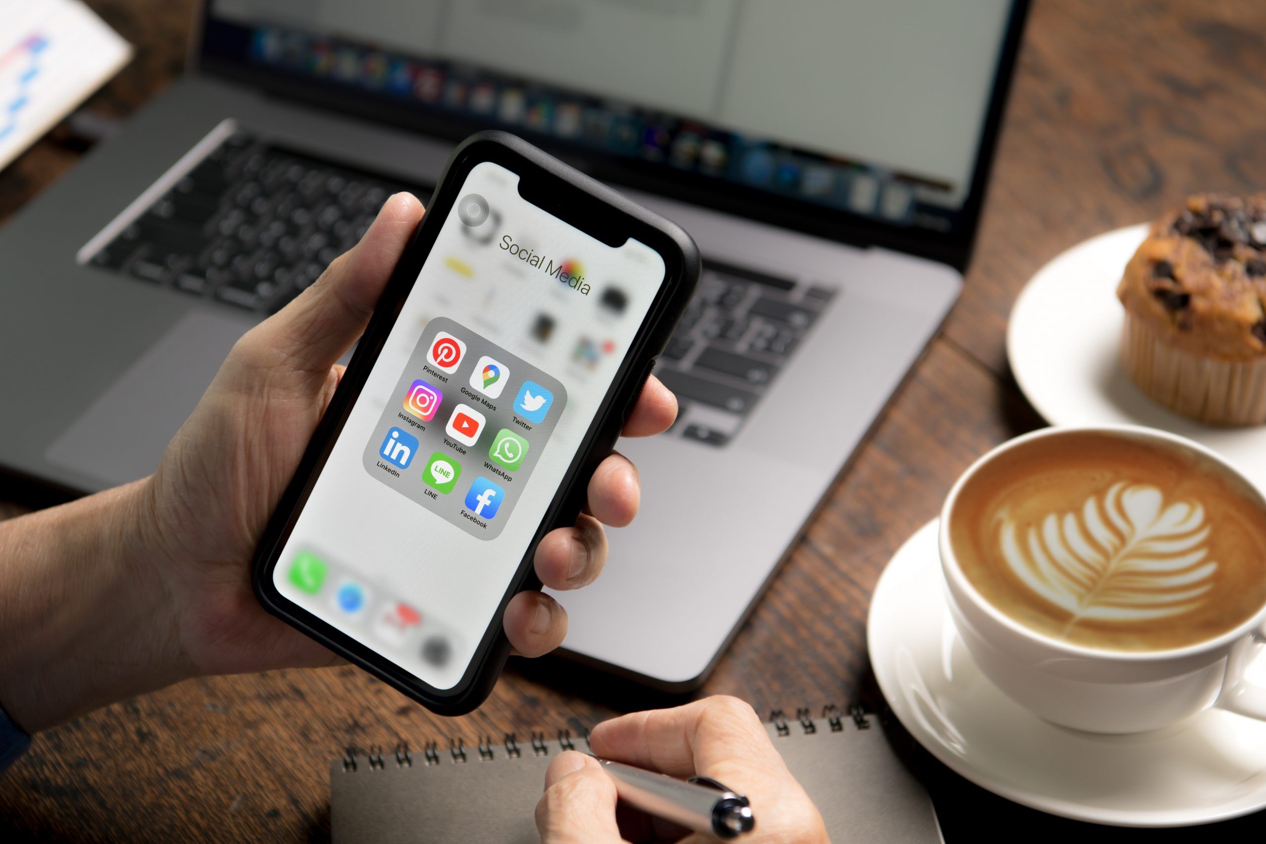 Blog 21 person holding smartphone with icons social media screen coffee shop scaled